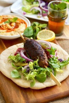 a wooden cutting board topped with meat and veggies