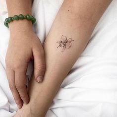 a woman's arm with a small flower tattoo on the left side of her arm