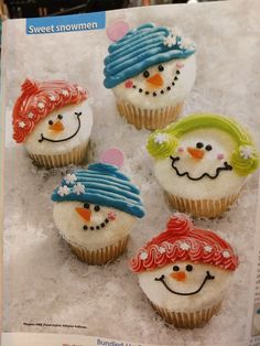 four cupcakes decorated with frosting and icing are sitting in the snow