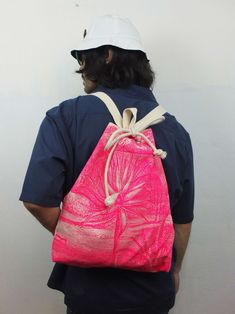 a person wearing a white hat and blue shirt with a pink bag on their back