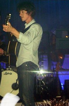 a man standing on top of a stage holding a guitar