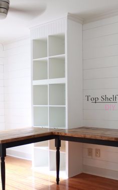 an empty room with a wooden table and white bookcases