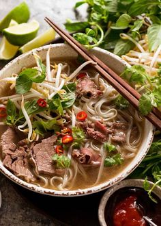 a bowl of beef pho noodle soup with chopsticks