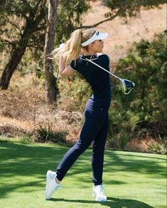 a woman swinging her golf club on the green