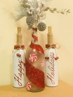 three bottles with candy canes and pine cones in them are sitting on a table