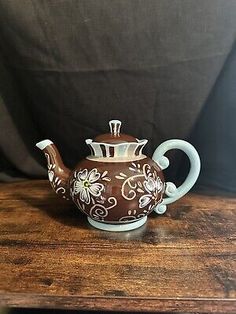 a brown and white tea pot sitting on top of a wooden table