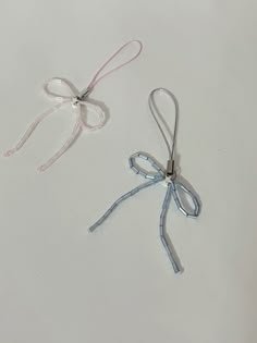 two ribbons tied together on a white surface with one knot in the middle and another string at the end