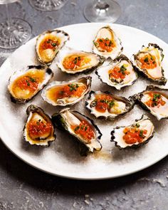 several oysters on a white plate with red sauce