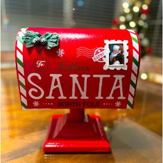 a red mailbox with a christmas card on it's front and the word santa written in white