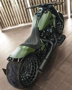 a green and black motorcycle parked on top of a wooden floor next to a fence