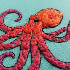 an orange and pink octopus is on a blue surface with red thread in the middle