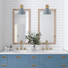 a bathroom with two mirrors and blue cabinets