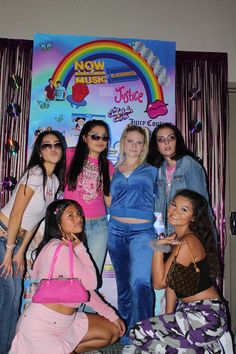 a group of young women posing for a photo in front of a rainbow sign and curtain