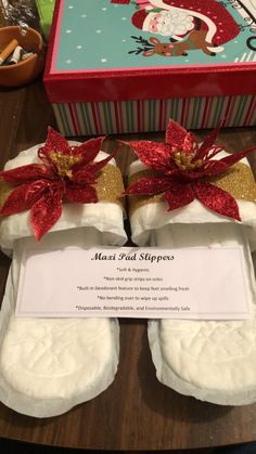 two white slippers with red bows on them sitting in front of a christmas box