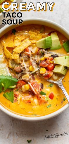 a bowl of creamy taco soup with tortilla chips and avocado