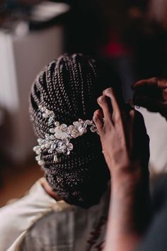 a woman is getting her hair combed by another person's hand and wearing a head piece