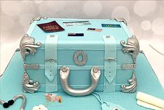 a cake that looks like a suitcase with silver handles and decorations on the top is sitting on a table