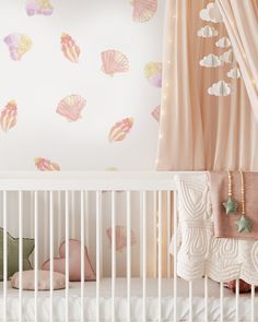 a baby's crib with pink curtains and seashells on the wall