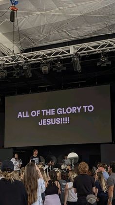 a group of people standing in front of a large screen with the words all of the glory to jesus on it