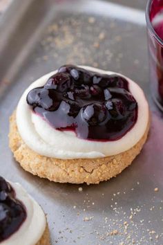 cookies with blueberry sauce and whipped cream are on a cookie sheet next to a glass of juice