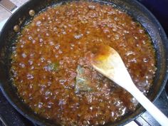 a wooden spoon in a pot filled with chili and beans on the stove top next to an oven