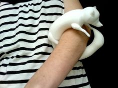 a woman wearing a striped dress holding a white cat shaped object in her arm with black and white stripes on it