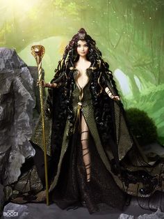 a barbie doll dressed in black and gold holding a staff standing next to a rock