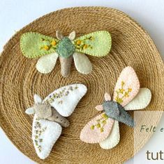 three handmade butterflies sitting on top of a woven plate with the words felt creations written below it