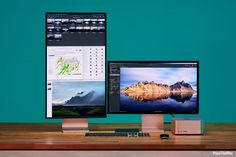 two computer monitors sitting on top of a wooden desk