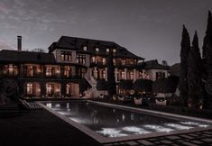 a large house with a pool in front of it at night, lit up by lights