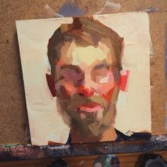 a painting of a man's face on a piece of paper next to shoes