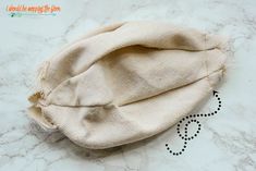 an unmade hat sitting on top of a white marble counter next to a pair of scissors