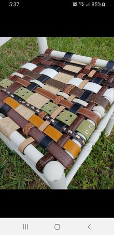 a chair made out of old belts on the grass