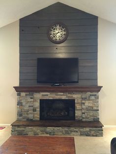 a living room with a stone fireplace and flat screen tv mounted on the wall above it