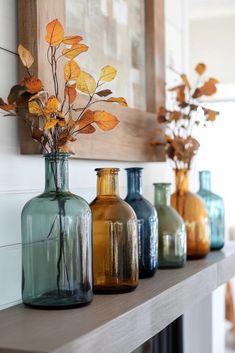 three vases with flowers are sitting on a shelf