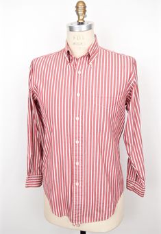 "\"The New Englander\" vintage 1980s button-down shirt by iconic American outfitter L.L.Bean in classic red, white and blue stripe pattern, featuring high quality cotton blend poplin, button-down collar, 6-button front (plus top collar button), chest pocket, long sleeves with single-button cuffs and box pleat in back--Beautiful condition!  SIZE: Tagged Size 15.5/33 Neck/Sleeve (Men's Small)    Shown on Size 40 Mannequin MEASUREMENTS*: Shoulder: 17\" Chest (underarm to underarm): 22\" Waist: 20\" Red Shirt With Striped Collar For Spring, Casual Red Dress Shirt For Spring, Red Casual Dress Shirt With Button Closure, Casual Red Dress Shirt With Button Closure, Classic Striped Button-up Shirt, Red Long Sleeve Shirt With Vertical Stripes, Red Cotton Shirt With Vertical Stripes, Classic Striped Dress Shirt For Summer, Classic Striped Summer Dress Shirt