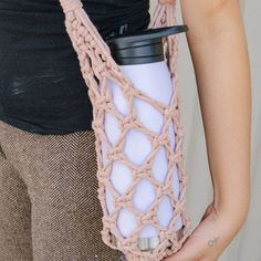 a woman holding a coffee cup in her hand with a crocheted bag around it