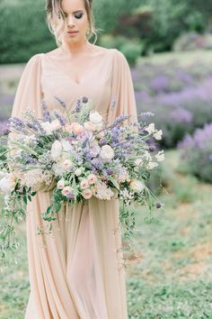 a woman holding a bouquet of flowers in her hand and wearing a dress with long sleeves