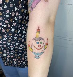 a woman with a tattoo on her arm has an ice cream cone in the shape of a clown