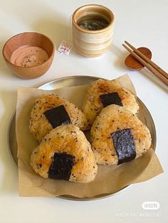 three pastries on a plate with chopsticks next to it and some dipping sauce