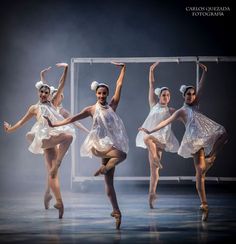 four ballerinas in white tutu skirts and headbands are dancing on stage