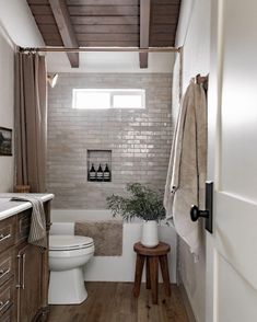 a white toilet sitting next to a bath tub in a bathroom on top of a hard wood floor