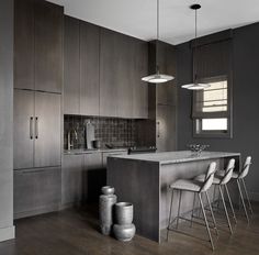 a kitchen with an island and stools in the center, surrounded by dark wood cabinets