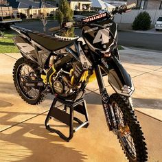 a dirt bike sitting on top of a stand in front of a house with no one around it