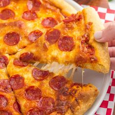 two slices of pepperoni pizza on a plate with red and white checkered table cloth