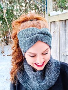 a woman with red hair wearing a gray headband and black sweater in the snow