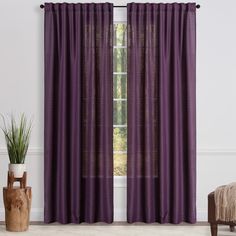 the purple curtains are hanging in front of a window with a potted plant next to it