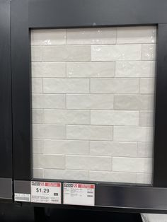 a white brick wall mounted to the side of a black metal frame in a store