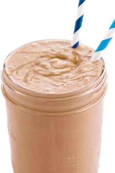 a smoothie in a mason jar with two blue and white striped straws