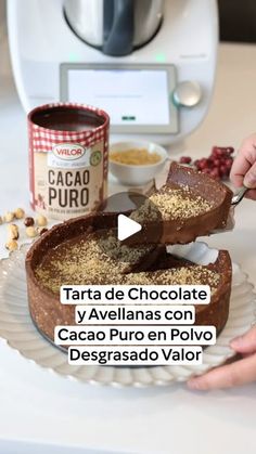 someone is cutting into a chocolate cake on a plate with cocoa and other ingredients in the background